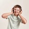 Portrait of happy disabled boy with Down syndrome in headphones listening to music and smiling at camera while standing