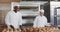 Portrait of happy diverse bakers working in bakery kitchen with fresh rolls in slow motion