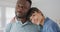 Portrait of happy diverse couple wearing jacket and shirt and embracing in living room