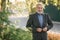 Portrait of happy elderly man in the park. Gray-haired bearded man in gray jacket