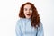 Portrait of happy excited woman with ginger curly hair, open mouth fascinated and amazed, stare at camera, checking out
