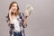 Portrait of a happy excited woman talking on mobile phone while holding bunch of money banknotes isolated over grey background