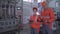 Portrait of happy factory workers men and female in helmets and overalls near conveyor line with tablets in hands during