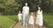 Portrait of a happy family with children holding hands and walking in a picturesque green garden on a sunny day