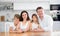 Portrait of happy family - father and mother with two children at table at home