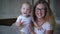 Portrait of happy family, merry mother in glasses holds infant on hands and looks on camera close up