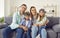 Portrait of a happy family sitting on the sofa at home with their two kids in pilot's glasses.