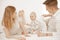 Portrait of happy family of three on white background. Mother, father and infant baby lie on bed. Photo of young couple