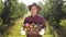 Portrait of happy farmer in hat standing at apple garden