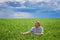 Portrait of a happy farmer kneeling down in a wheat field with a beautiful landscape in the background