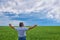 Portrait of a happy farmer kneeling down in a wheat field with a beautiful landscape in the background