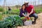 Portrait of happy farmers with basket of ripe vegetables on the field