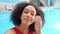 Portrait happy female face, closeup curly Afro vlogger make stream live video from spa pool complex for blog, waves hand