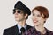 Portrait of happy female flight attendant and pilot against gray background