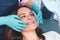 Portrait of happy female patient sitting in dentist chair, smiling and examining her teeth in the mirror, dental surgeon showing