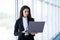 Portrait of happy female startup employees standing at office doorway with laptop