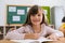 Portrait of happy female student sitting at desk in classroom smiling. Cute Caucasian elementary school girl sitting in