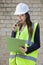 Portrait of a happy female supervisor with clipboard standing at construction site