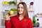 Portrait of happy female vegeterian holds fresh apple, stands near fridge with happy expression, keeps to diet, has fridge full of