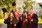 Portrait of happy five graduates in robes holding mortar-board with tassel