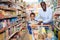 Portrait of happy friendly African family of father and tween son shopping in supermarket