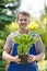 Portrait of happy gardener holding potted plant at nursery