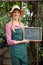 Portrait of happy gardener with open text on chalkboard at garden