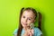 Portrait of happy girl with colored sweet Lollipop on stick on green background