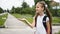 Portrait of happy girl with school bag standing outdoor. Little happy school girl going to school, back to school, education