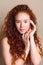 Portrait of happy girl smiling on camera on beige background. Model with curly red hair and perfect skin with little freckles