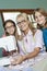 Portrait of happy granddaughters with grandmother sewing cloth