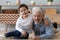 Portrait happy grandfather and little grandson sitting on warm floor