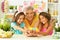 Portrait of happy grandmother and granddaughters coloring Easter eggs