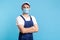 Portrait of happy handyman in overalls and cap standing with crossed hands, profession of service industry