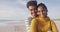 Portrait of happy hispanic couple standing and embracing on beach