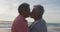Portrait of happy hispanic senior couple kissing on beach at sunset