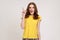 Portrait of happy inspired woman of young age in yellow casual T-shirt raising finger and having