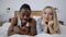 Portrait of happy joyful interracial couple posing lying on bed at home. Cheerful handsome African American tattooed man