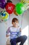 Portrait of happy kid boy with bunch on colorful air balloons on his birthday. Smiling school child having fun