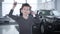 Portrait of happy little caucasian boy jumping in showroom holding car keys. Parents standing next to car at the