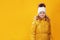 Portrait happy little girl preschooler in a winter jacket. Yellow on a yellow background