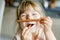 Portrait of happy little preschool girl holding chocolate waffle rolls. Smiling hungry toddler child with sweet biscuit