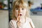 Portrait of happy little preschool girl holding chocolate waffle rolls. Smiling hungry toddler child with sweet biscuit wafer.