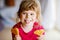 Portrait of happy little preschool girl holding fresh baked heart waffle. Smiling hungry toddler child with sweet