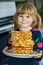 Portrait of happy little preschool girl holding fresh baked waffles. Smiling hungry toddler child with sweet biscuit