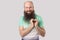 Portrait of happy in love middle aged bald man with long beard in green t-shirt standing with heart shape and looking at camera