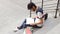 Portrait of a happy male asian student sitting on stairs and reading book