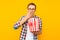 Portrait of a happy man in transparent glasses with a bucket of popcorn, keen on watching a movie, on a yellow background