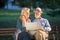 Portrait of happy man and woman reading map while sitting on a park bench. Senior couple on vacation using city map.