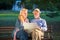 Portrait of happy man and woman reading map while sitting on a park bench. Senior couple on vacation using city map.